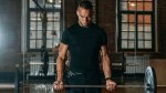 Fit young muscular man in his late 20's performing barbell bicep curls for more arm muscles and strength